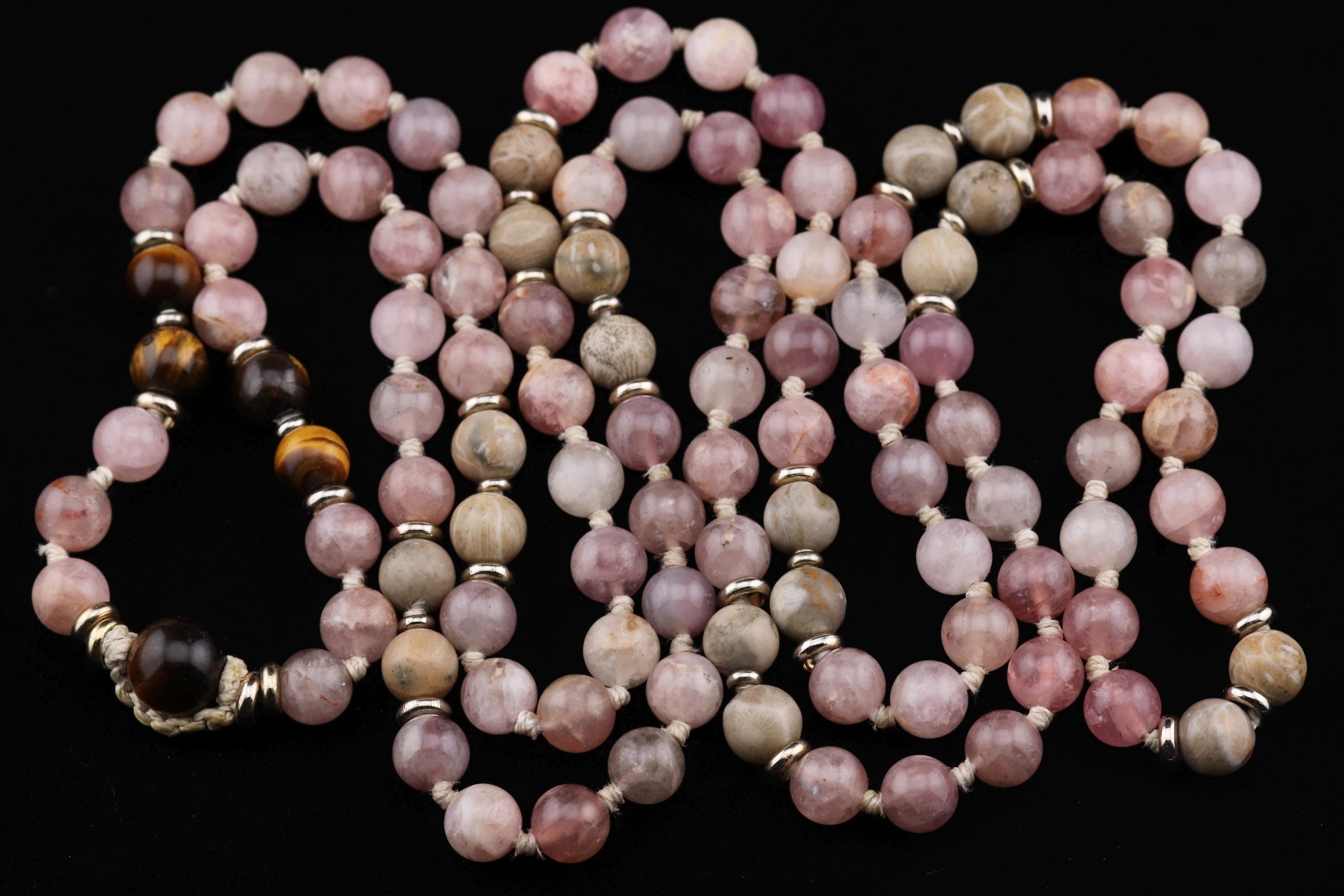 A necklace composed of numerous beads in various colors, including pink, gray, and brown, arranged in a decorative pattern.