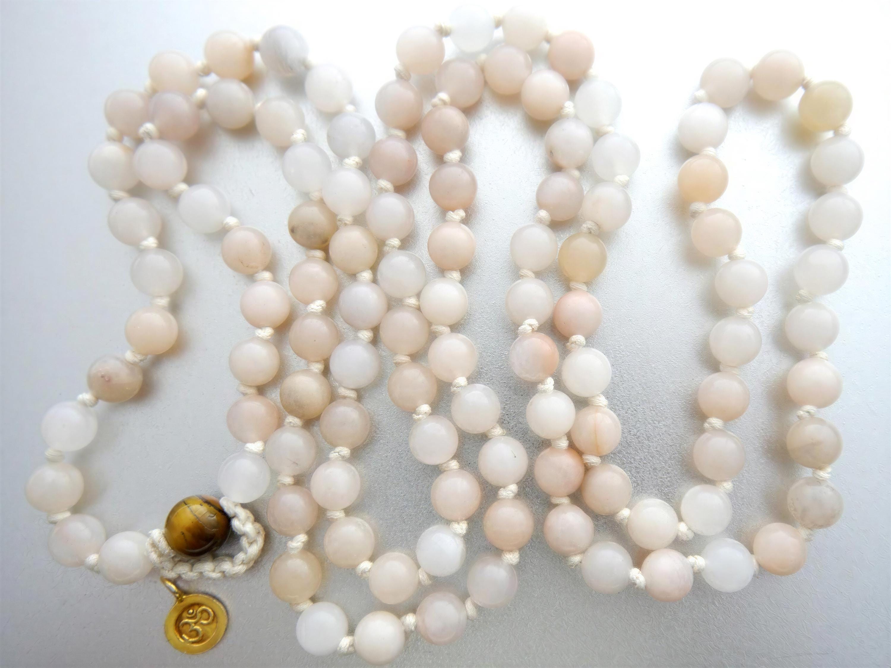 A beaded necklace with a pendant, featuring a variety of light-colored beads in shades of white, beige, and peach.