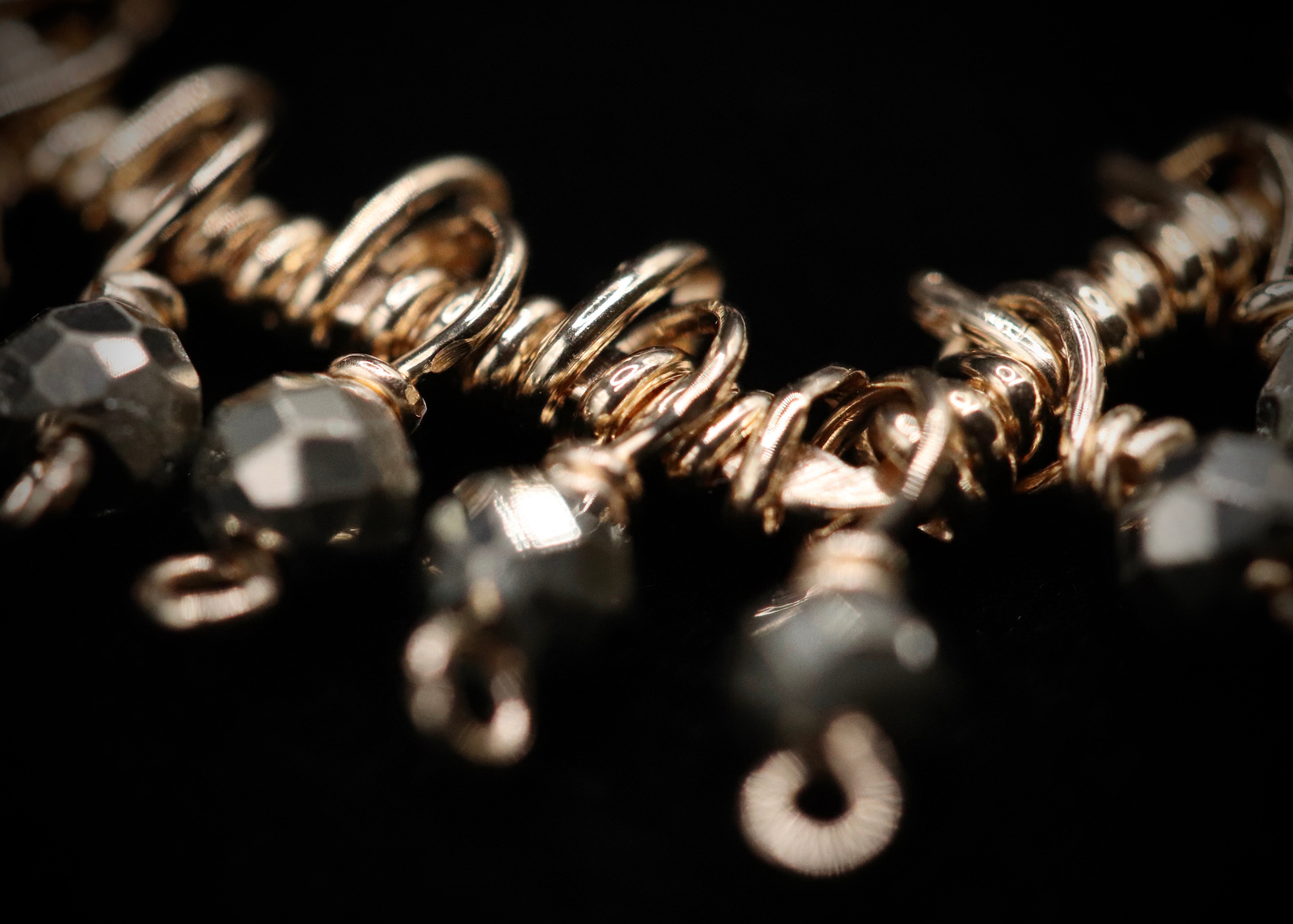 A close-up view of a piece of jewelry, possibly a necklace or bracelet, with a focus on the intricate details and textures of the metal and gemstones.