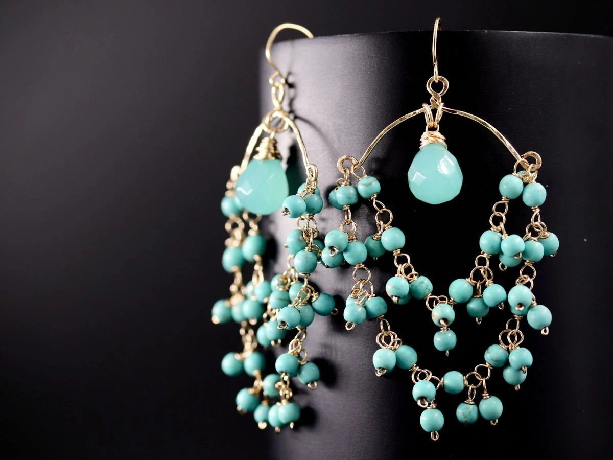 May include: Gold dangle earrings with turquoise beads and a light blue gemstone pendant.