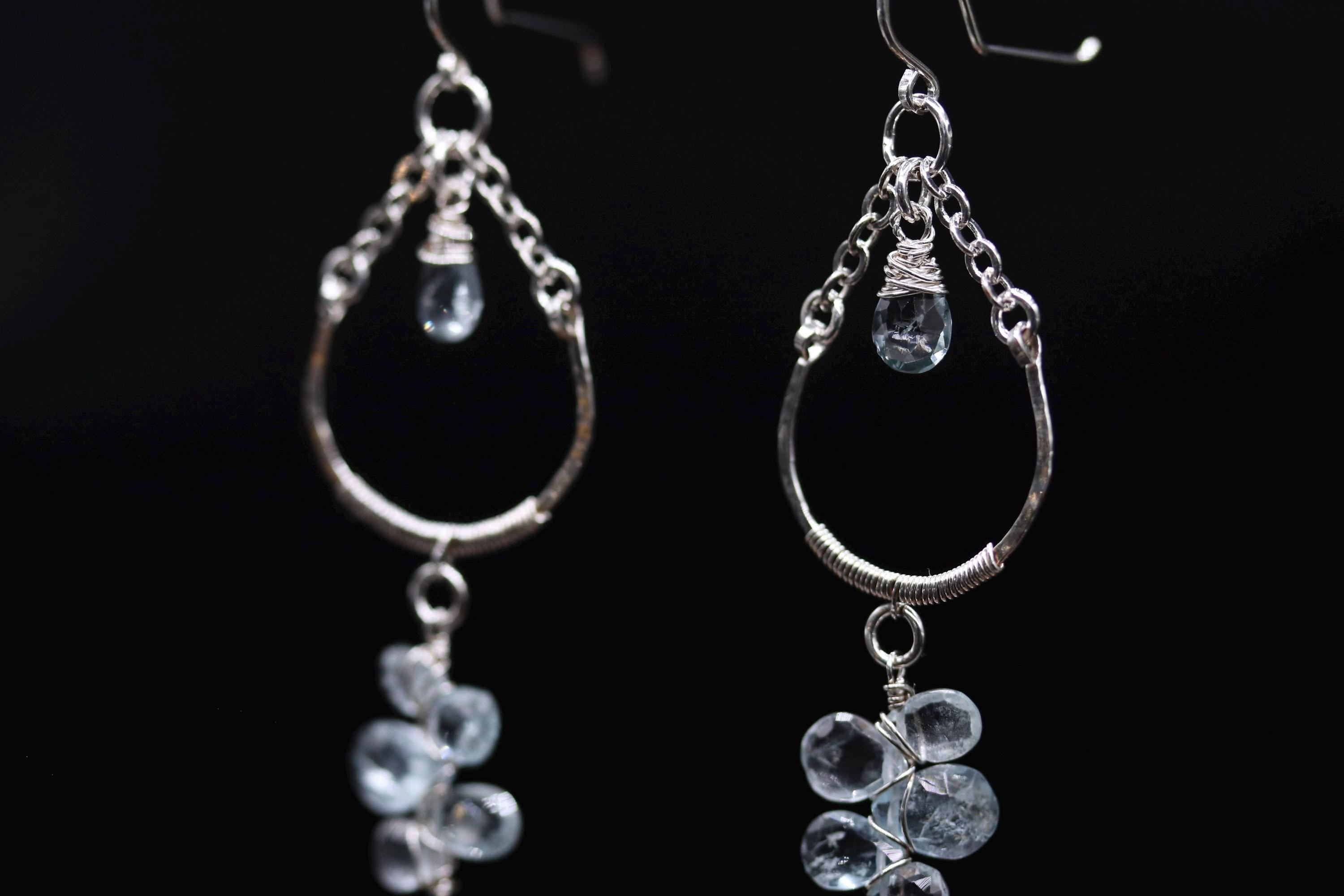 A pair of elegant earrings with clear gemstone accents and metal chains hanging from the ear hooks.