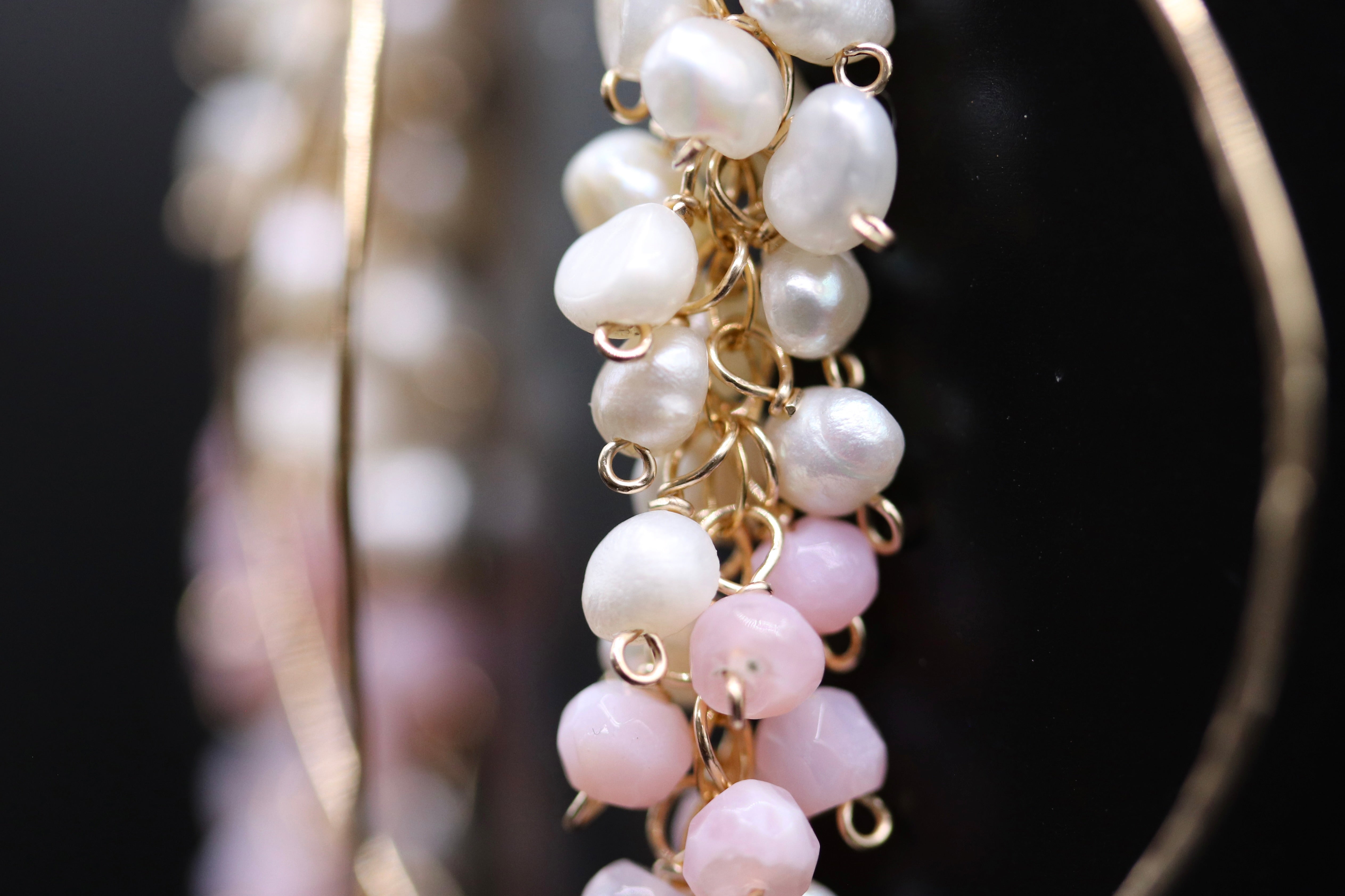 A close-up view of a delicate necklace with a combination of white and pink pearls and gold-colored beads.