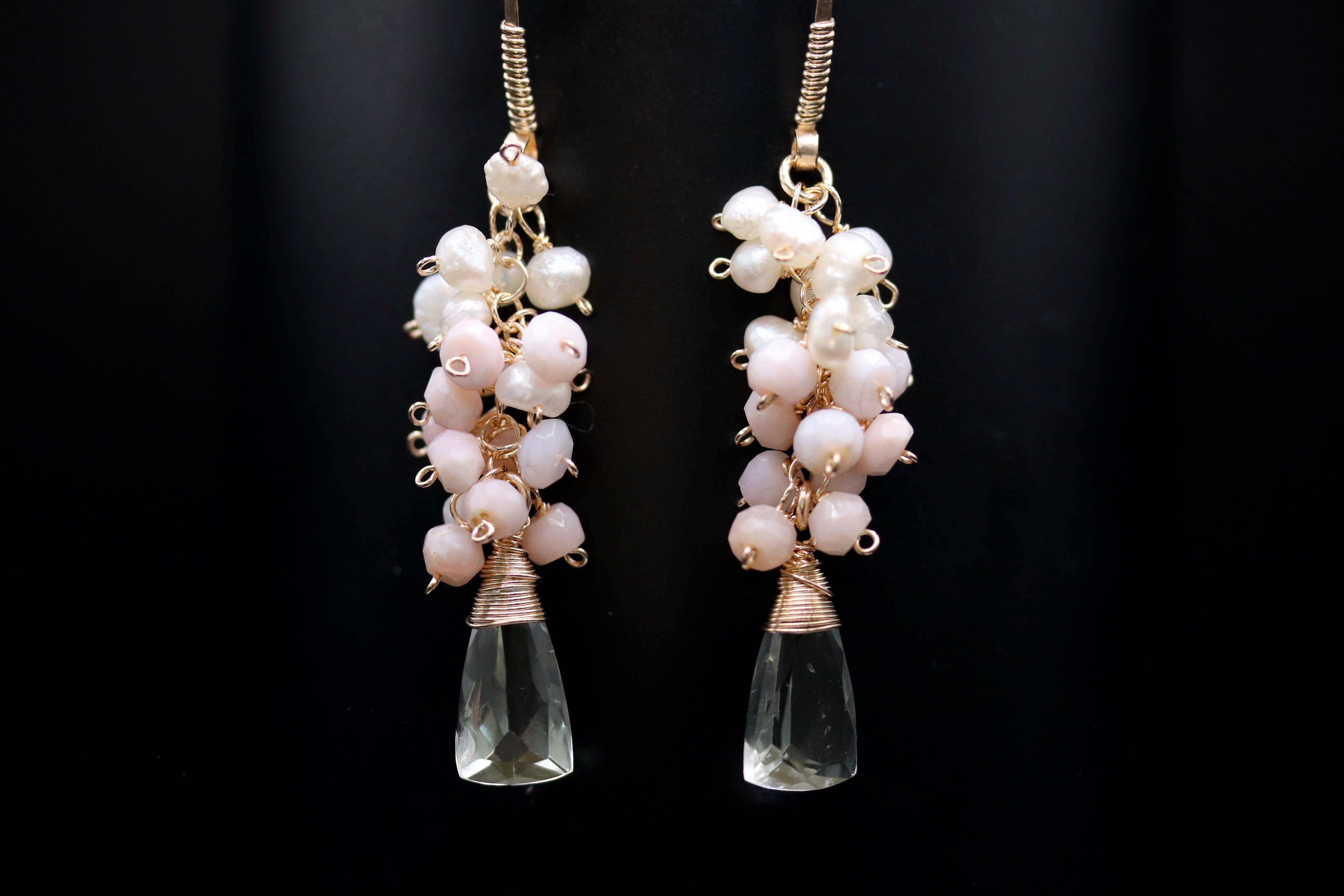 A pair of elegant earrings with clear gemstone pendants and white pearl-like beads hanging from the ends.