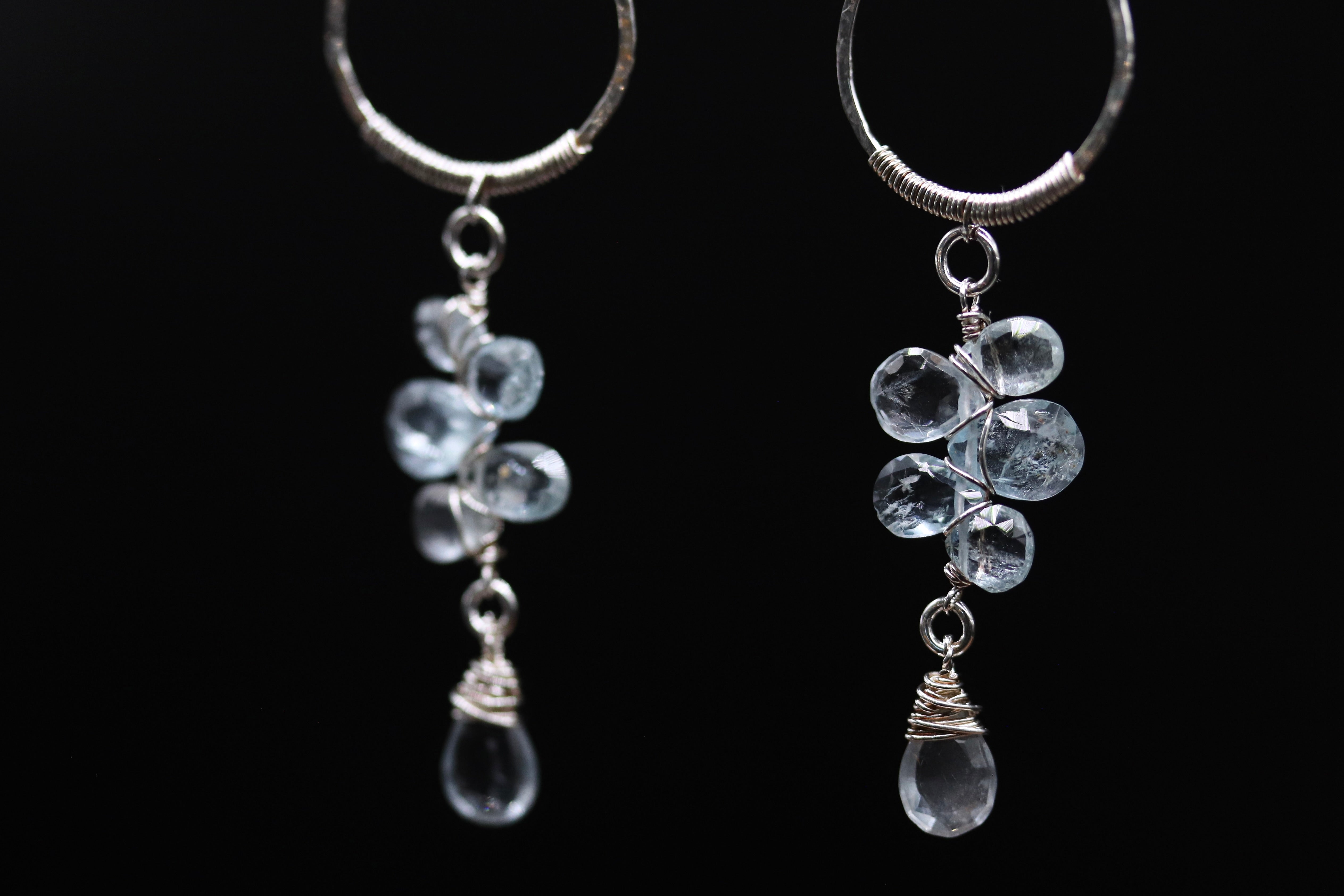 A pair of elegant earrings with clear gemstone accents, suspended from a circular metal frame.