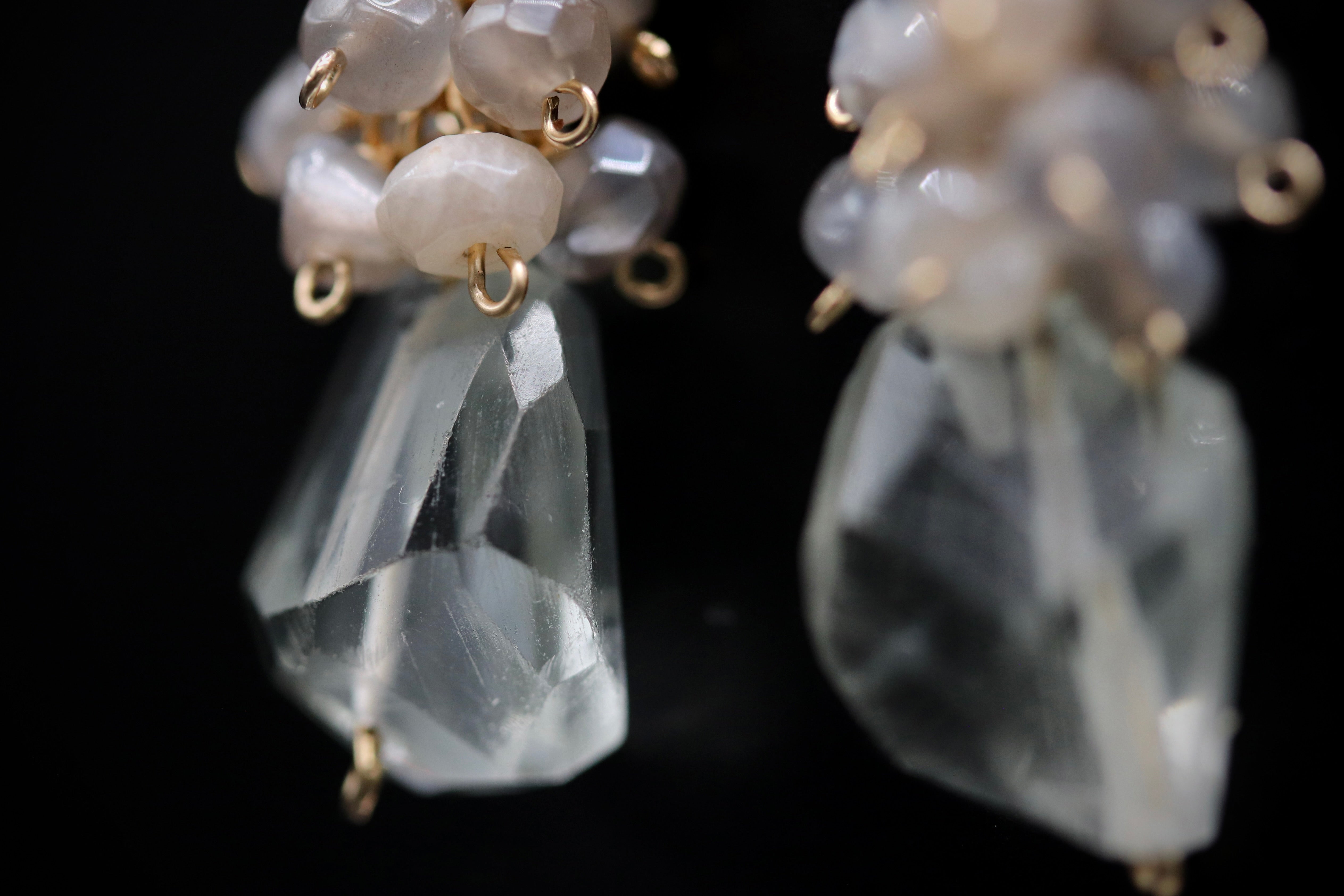 A close-up view of a pair of crystal earrings with clear gemstones and gold-colored metal accents.