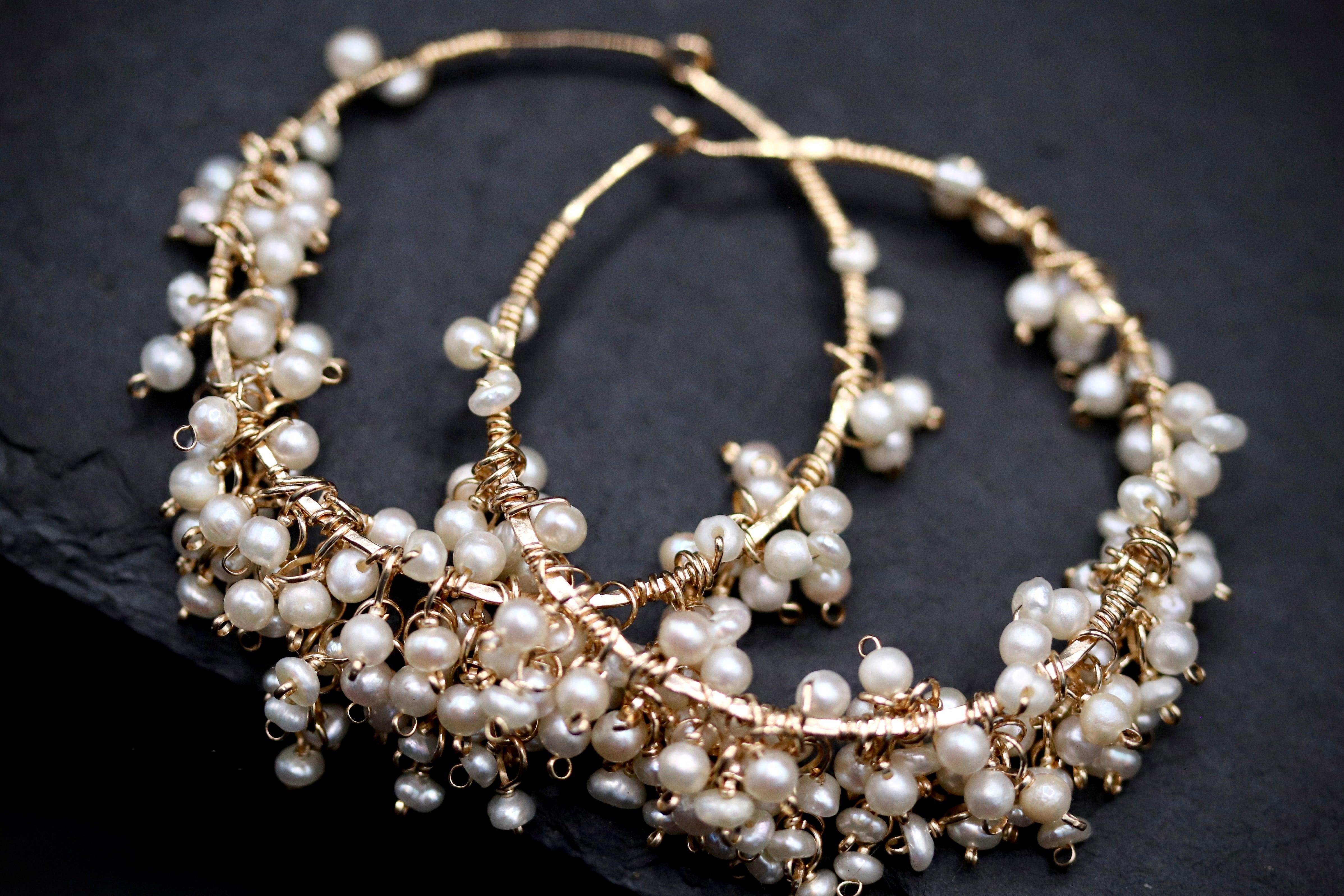 A pair of elegant gold hoop earrings adorned with numerous small white pearls, creating a delicate and sophisticated appearance.