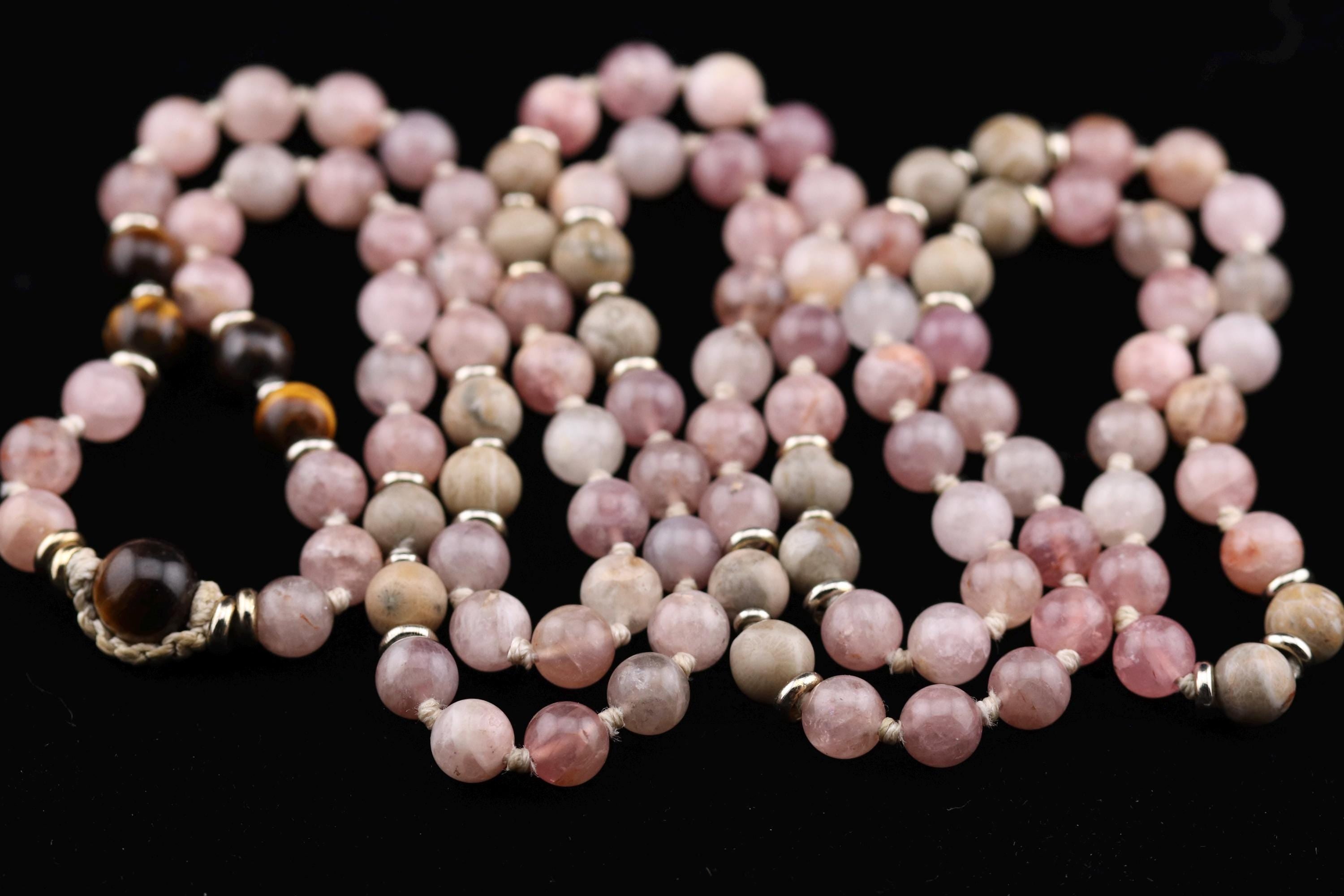 A close-up image of a beaded necklace with various shades of pink and brown beads arranged in a decorative pattern.
