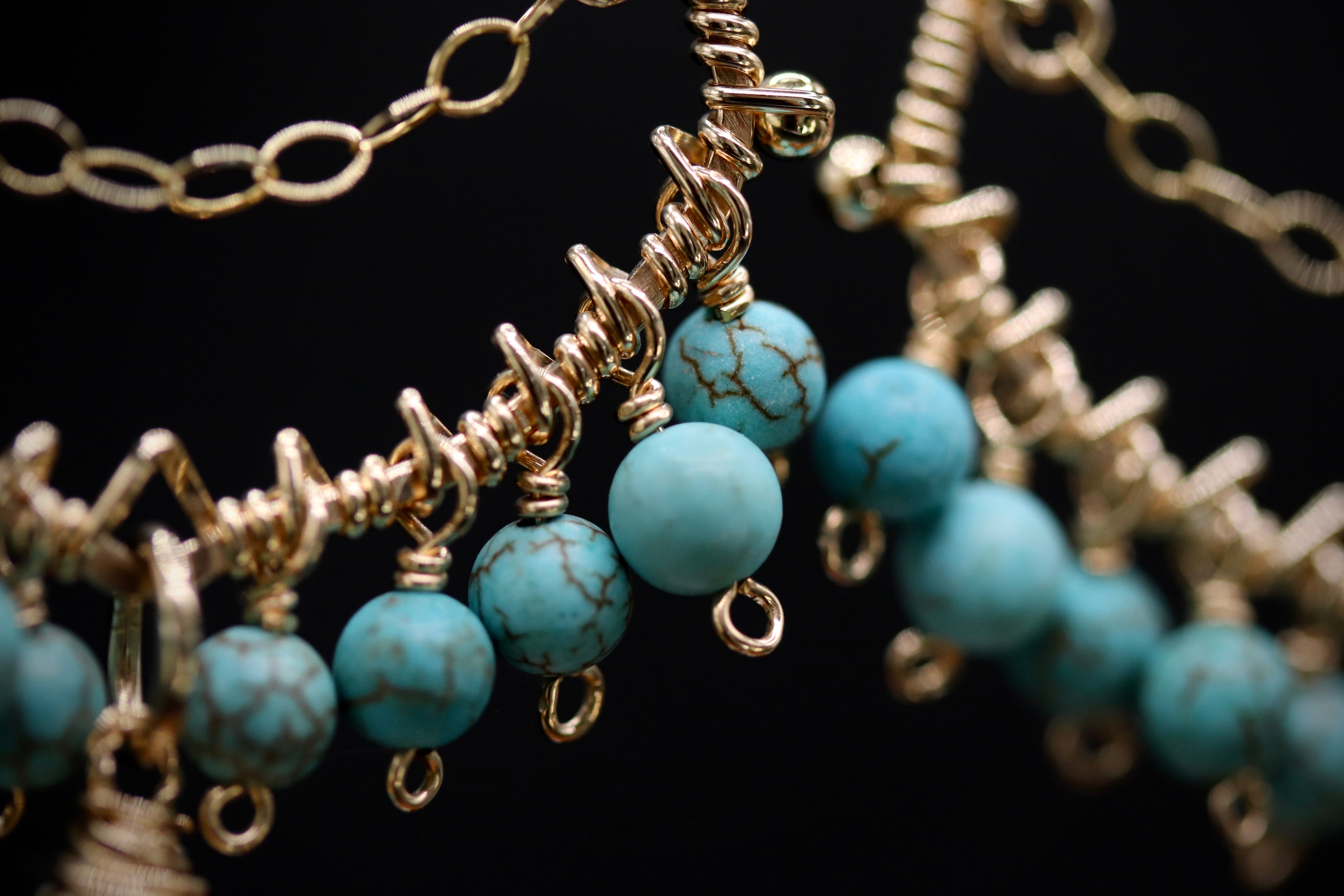 A close-up view of a necklace with turquoise beads and gold-colored metal chains.
