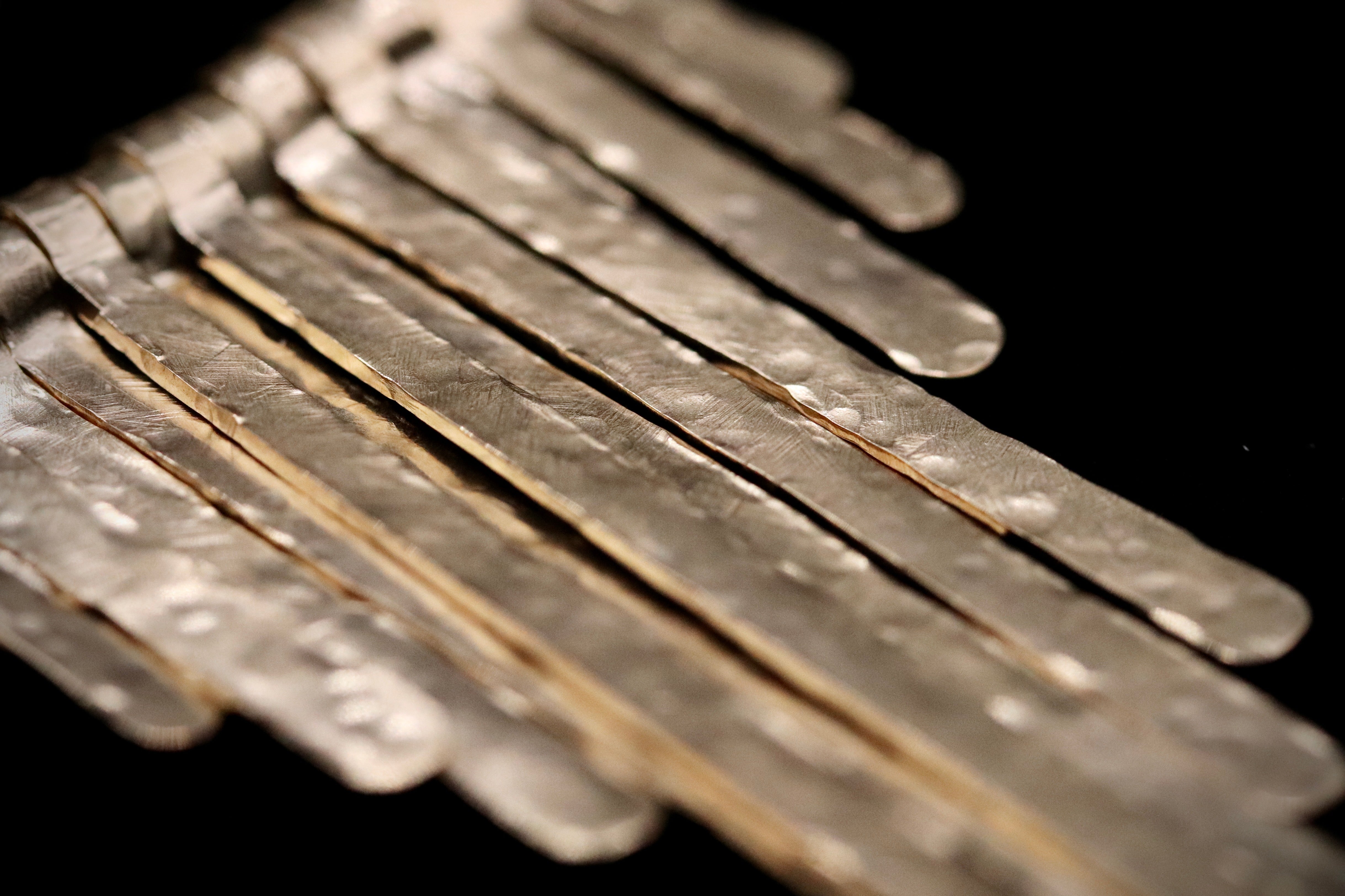 A close-up image of a collection of metal strips or rods arranged in a diagonal pattern against a dark background.