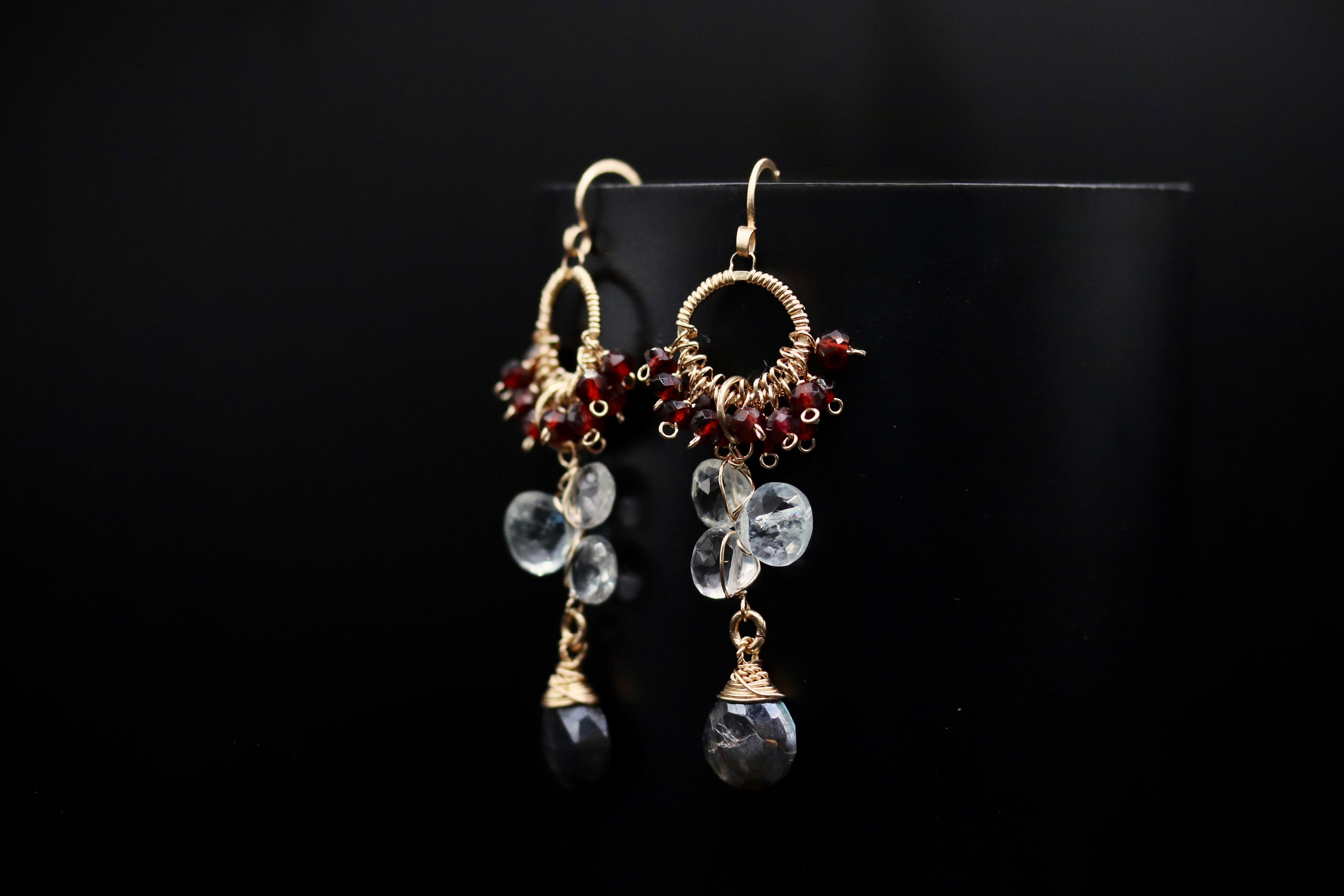 A pair of elegant earrings with clear gemstone accents and metal wire accents, hanging against a black background.