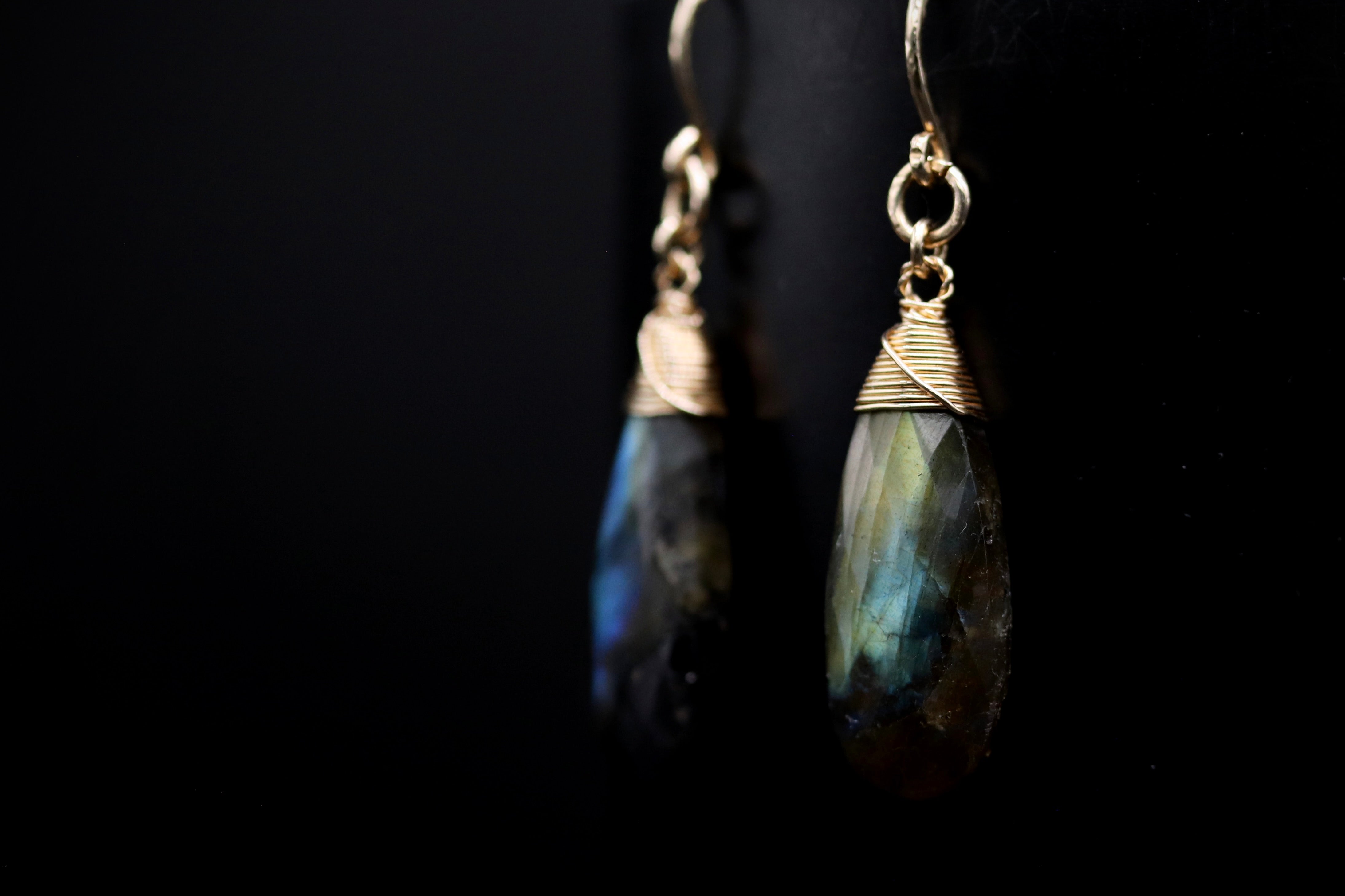 A pair of elegant earrings with a dark stone pendant and a gold-colored metal clasp.