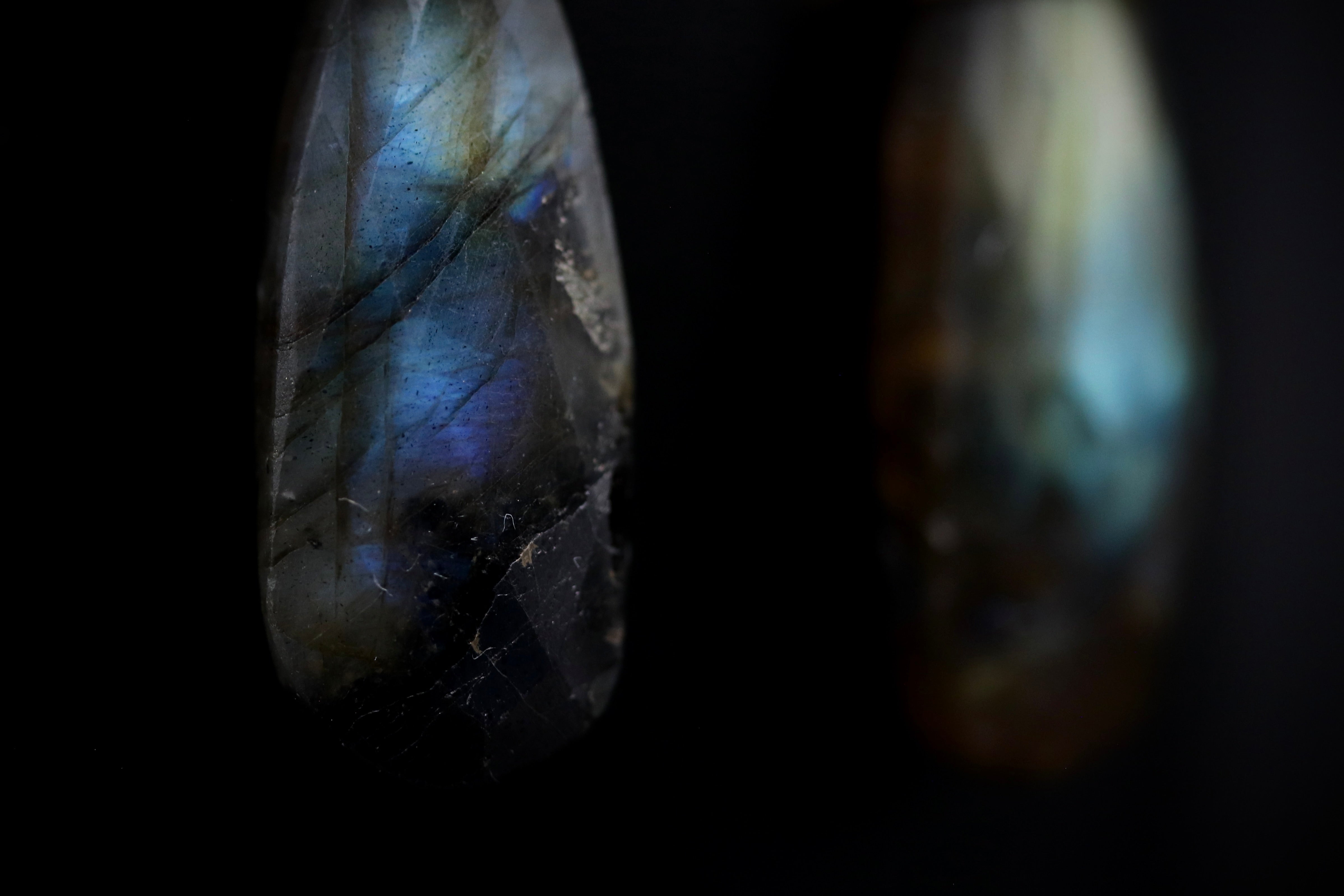 two close-up shots of a piece of jewelry, possibly a necklace or pendant, with a dark background. The jewelry appears to be made of a shiny, metallic material, possibly gold or silver, and has a unique, textured pattern. The focus of the image is on the intricate details and craftsmanship of the jewelry piece.