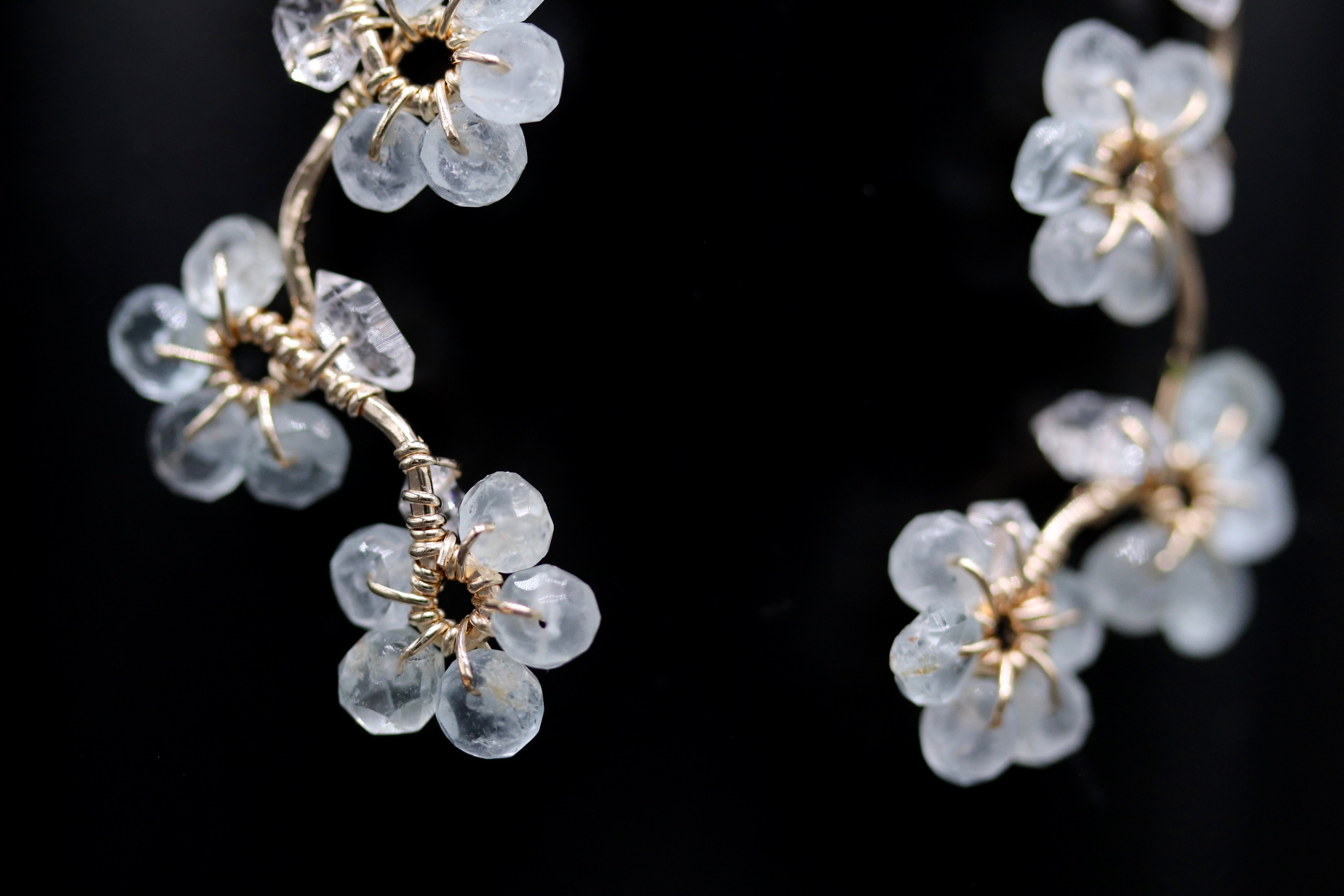 A close-up view of delicate, clear crystal flower-shaped earrings against a dark background.