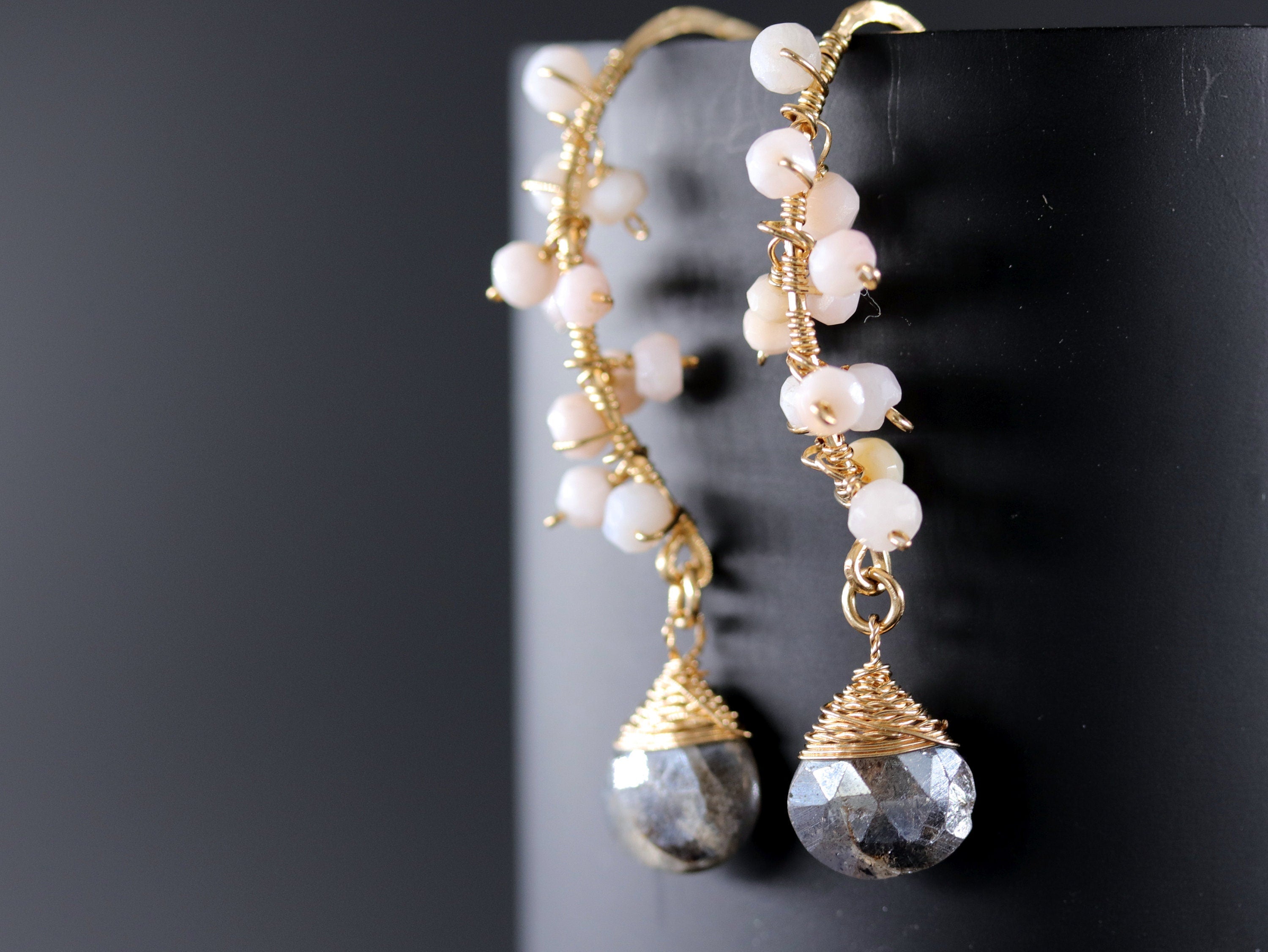 May include: A pair of gold earrings with a dangling gray stone and a cluster of small pink beads.