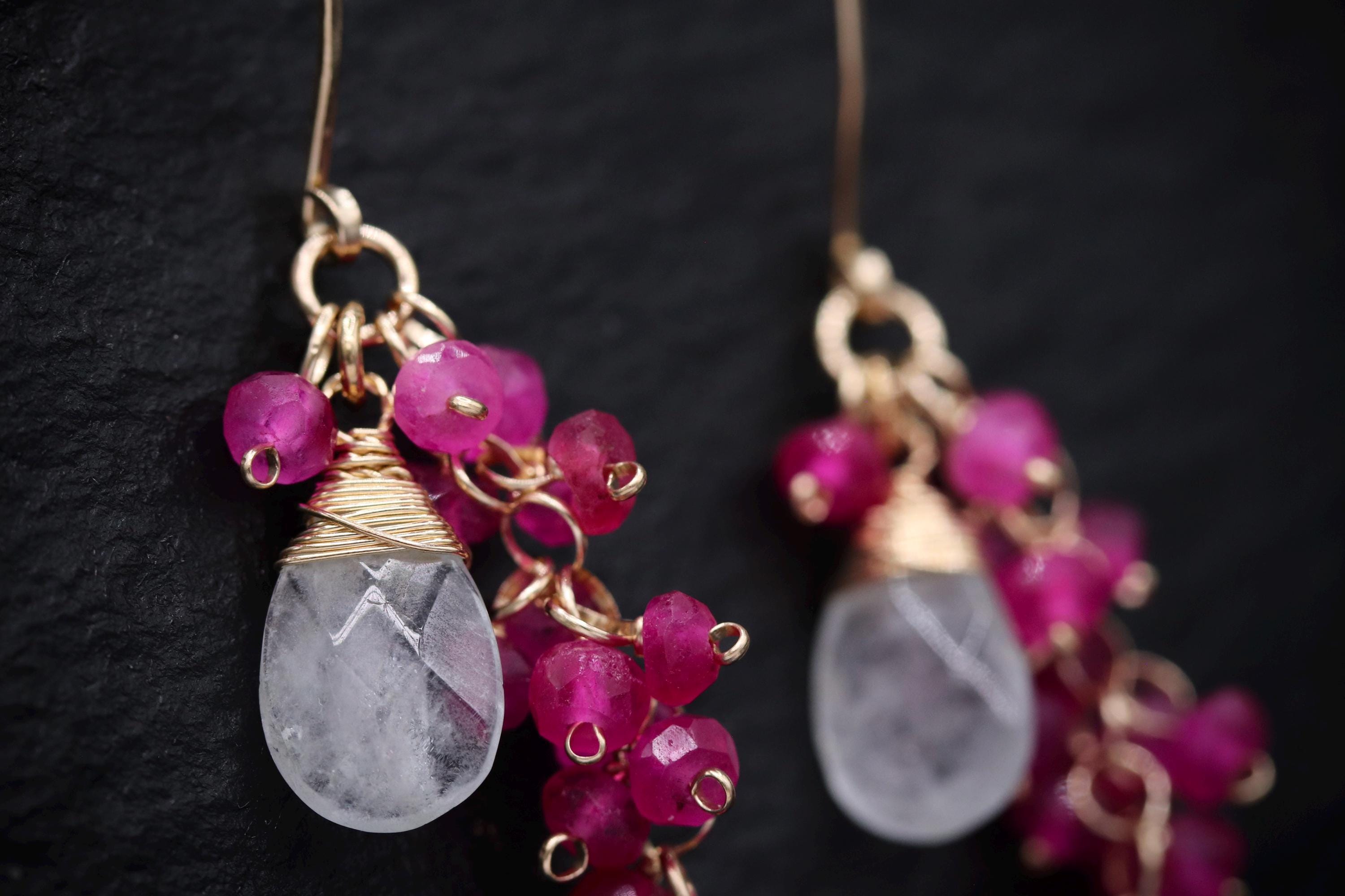 A close-up view of a pair of earrings with clear gemstone accents and gold-colored metal chains.