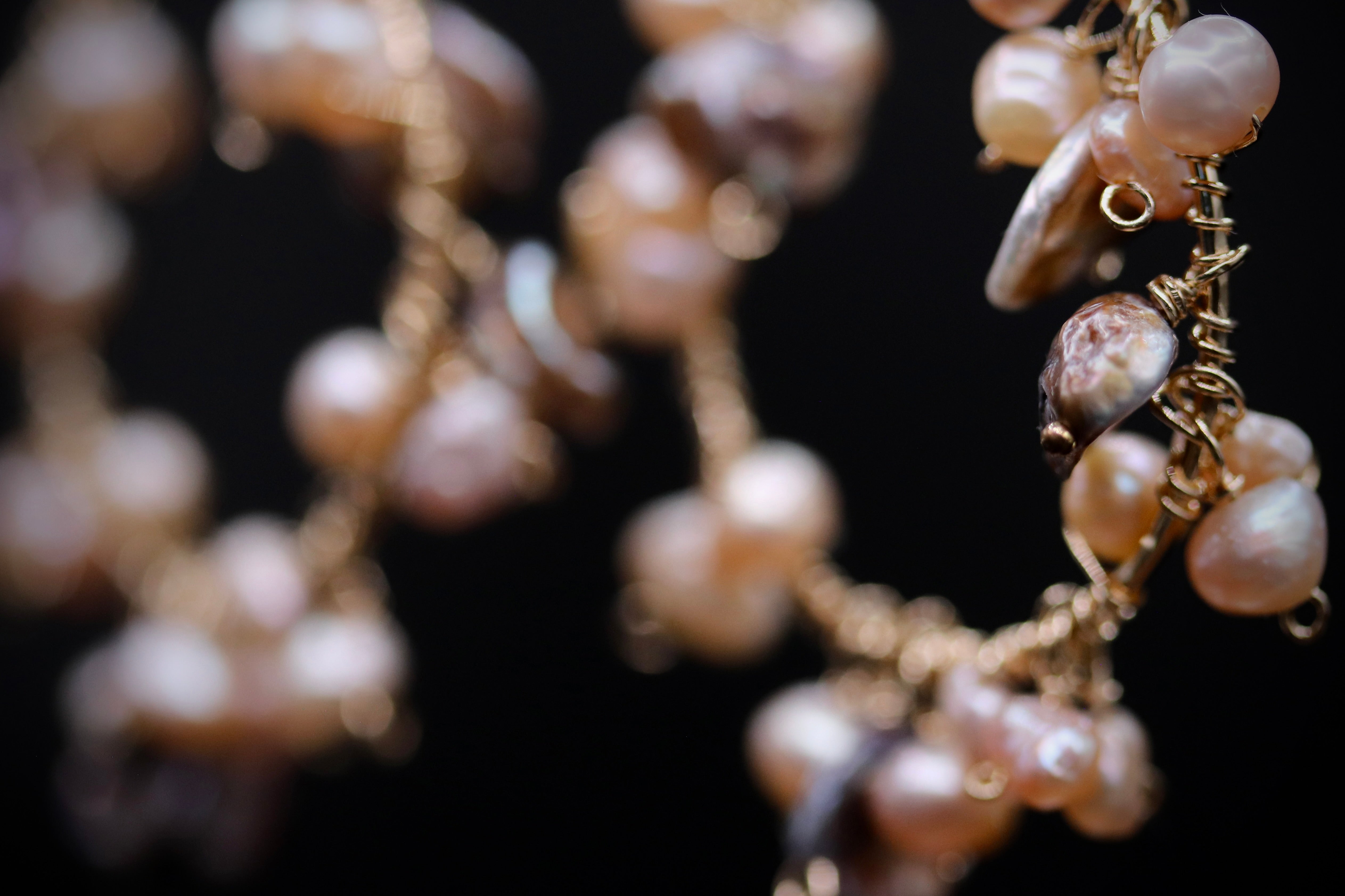 A close-up view of a delicate necklace with numerous small, round pearls and a metallic wire element.