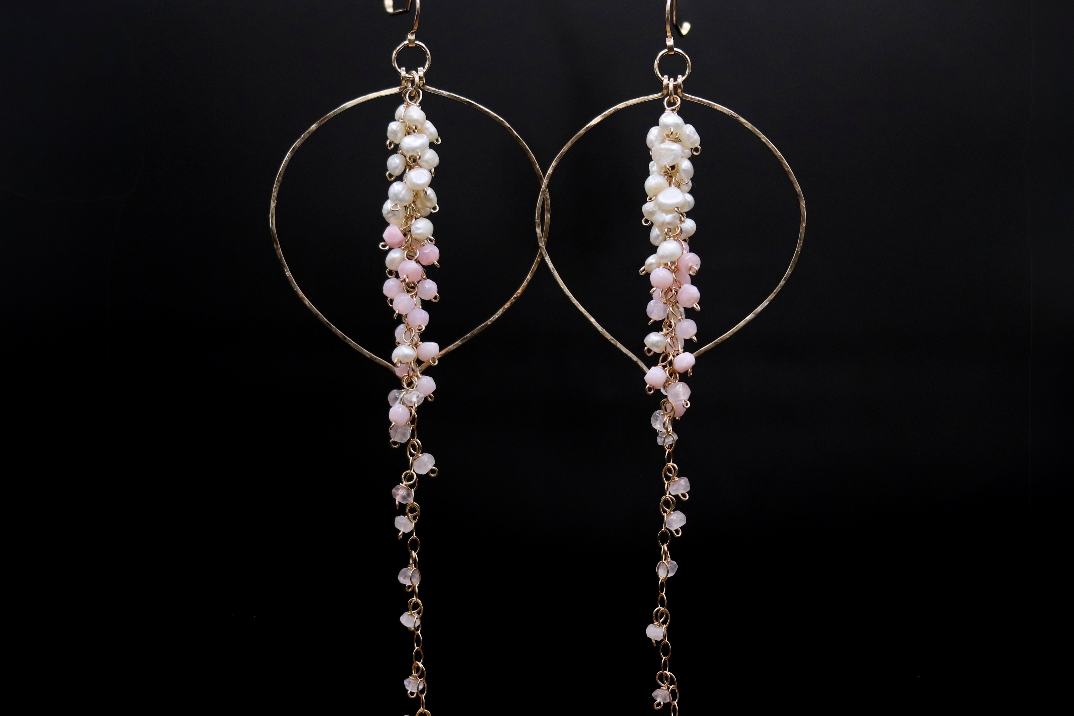 A pair of elegant earrings with a delicate chain and pearl design, featuring a circular hoop and a long, dangling chain.