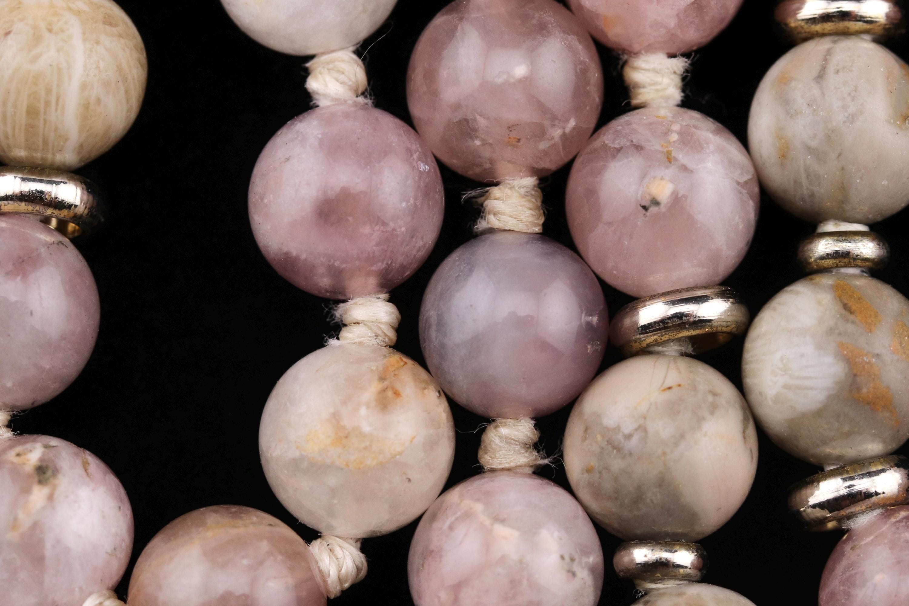 A close-up image of a collection of beaded jewelry, featuring a variety of pink and white stones arranged in a visually appealing manner.